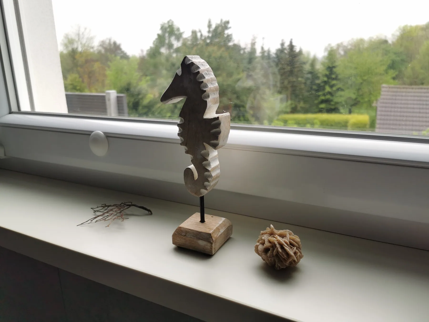 Badezimmerfenster mit Seepferdchen-Dekoration und Blick ins Grüne