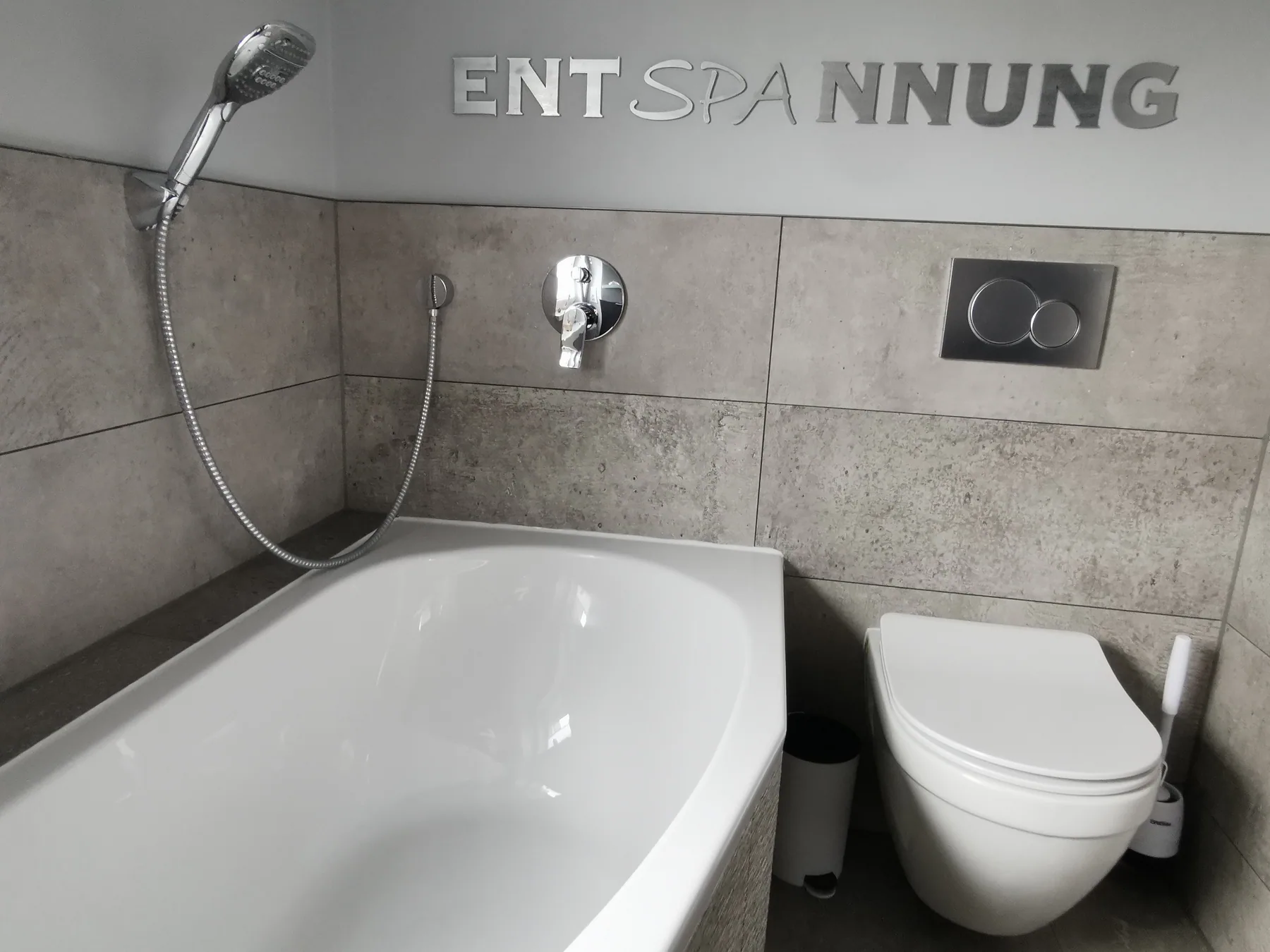 Badewanne und WC im modern gefliesten Badezimmer