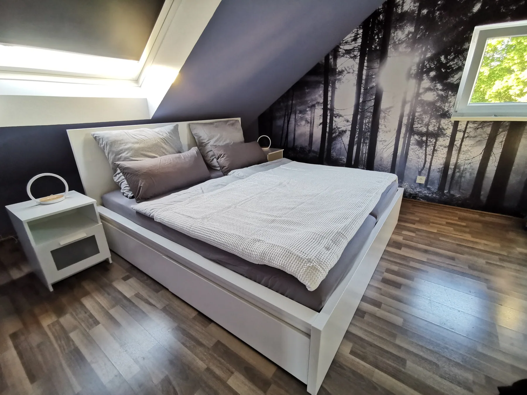 Hauptschlafzimmer mit Doppelbett und Waldmotiv an der Wand